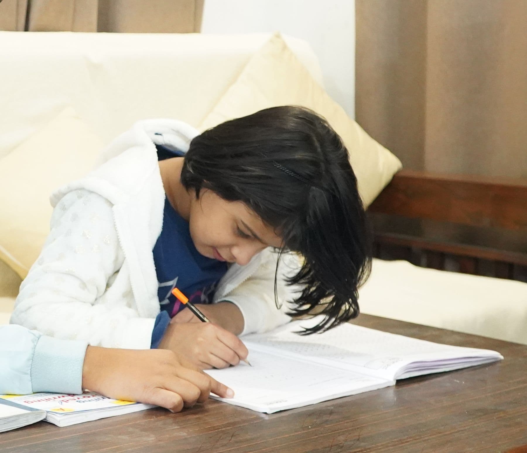 A young student writing in her notebook during a home tuition class